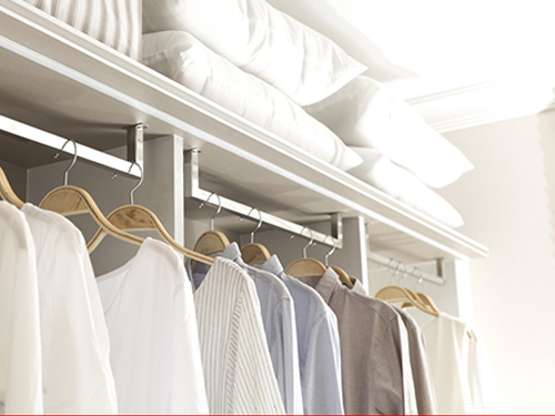Walk in closet with clothes on hangars. 